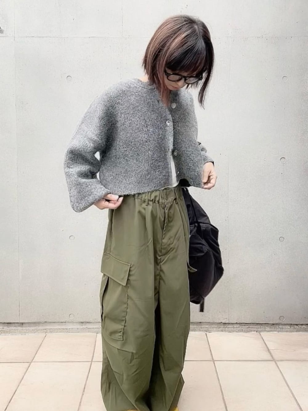 グレー系のカーディガン/ボレロ、ホワイト系のキャミソール、グリーン系のカーゴパンツを着用したレディースの秋コーディネートの4枚目の写真