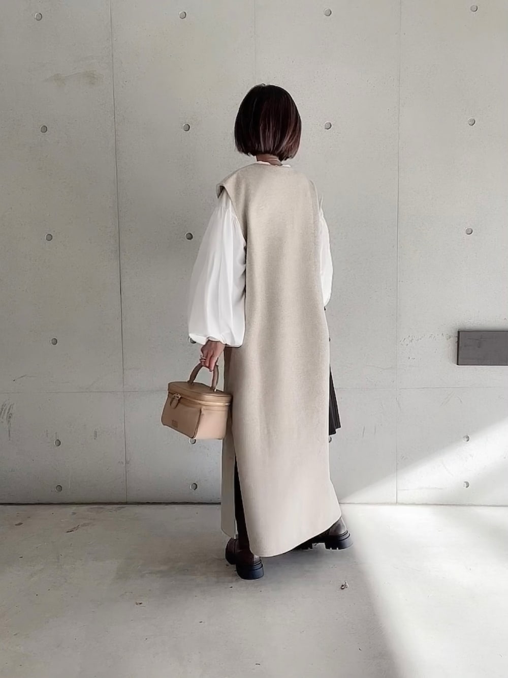 ベージュ系のワンピース、ホワイト系のシャツ/ブラウス、ブラウン系のブーツを着用したレディースの冬コーディネートの2枚目の写真