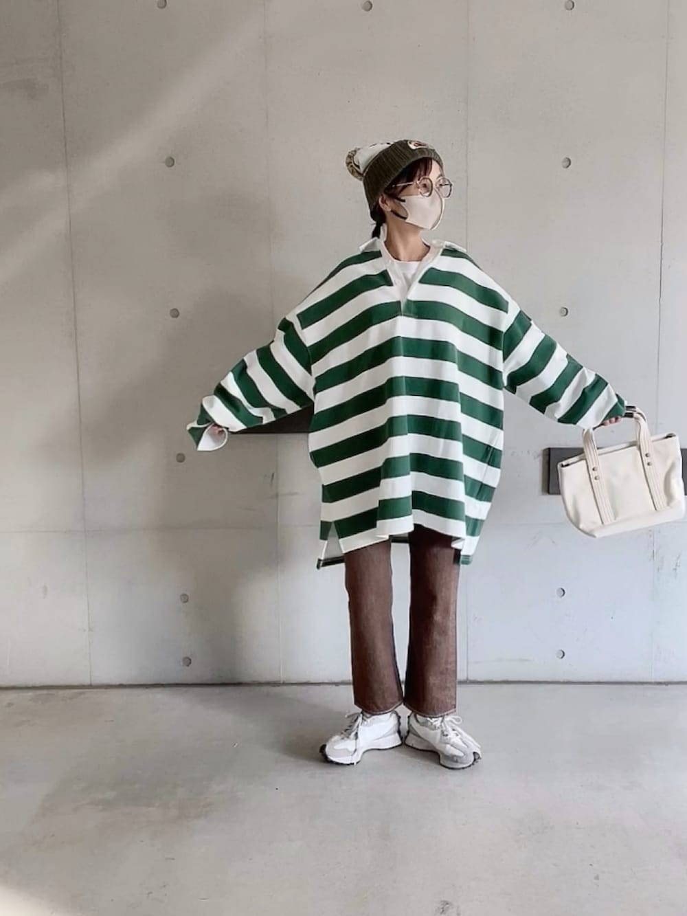 ブラウン系のデニムパンツ、ホワイト系のスニーカー、ホワイト系のトートバッグを着用したレディースの春コーディネートの4枚目の写真