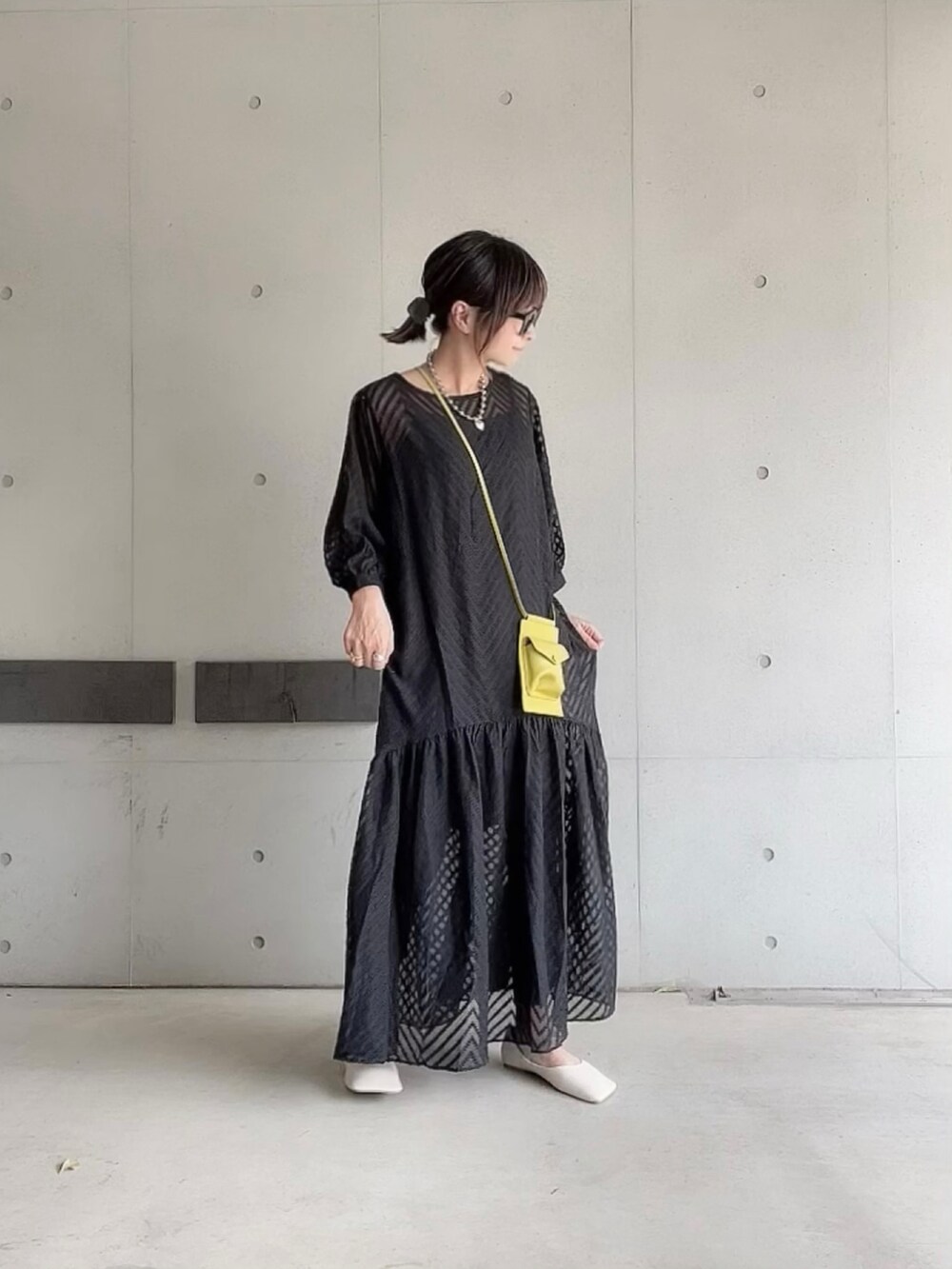 ブラック系のワンピース、グリーン系のショルダーバッグ、ホワイト系のパンプスを着用したレディースの夏コーディネートの2枚目の写真