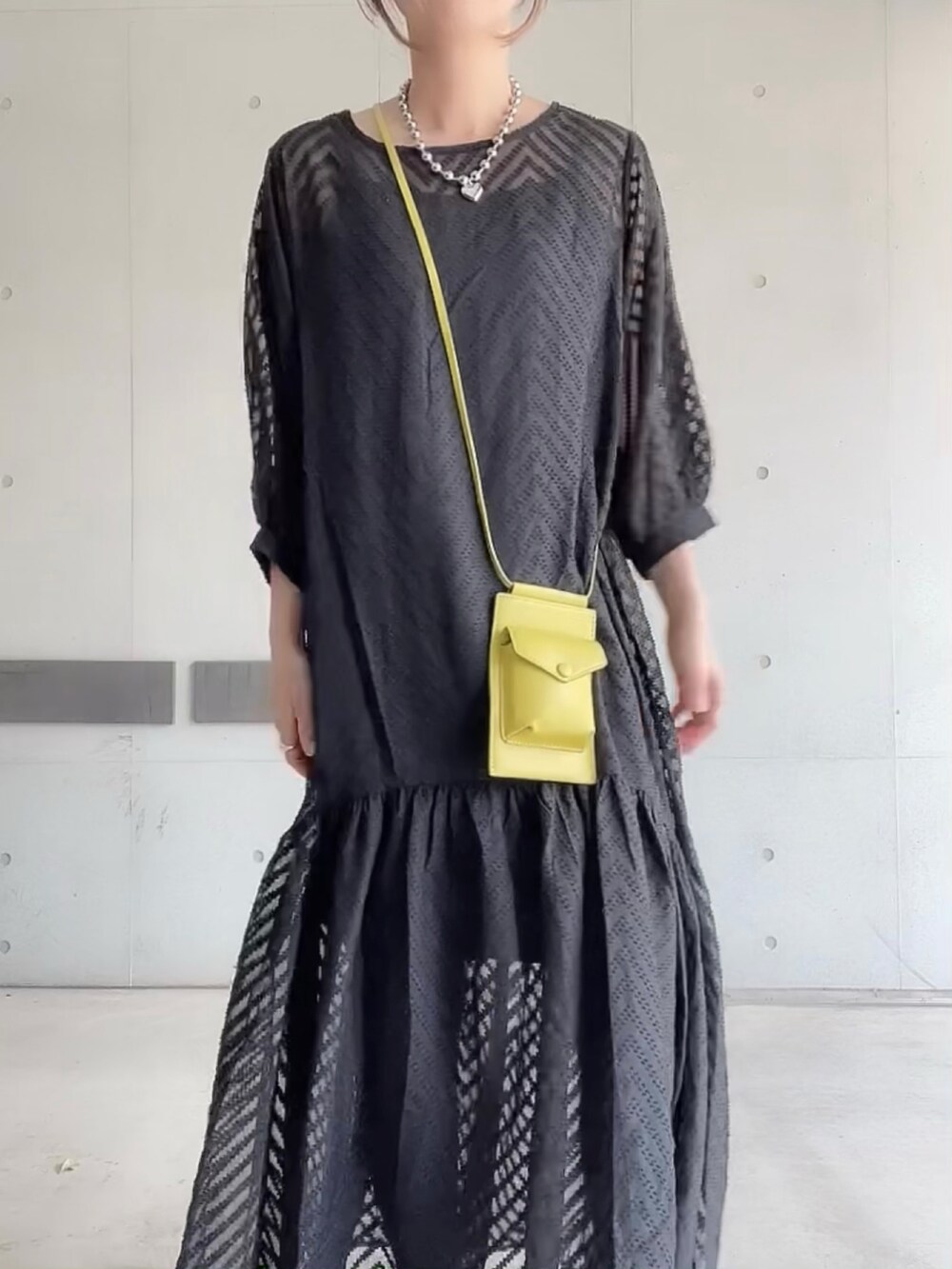 ブラック系のワンピース、グリーン系のショルダーバッグ、ホワイト系のパンプスを着用したレディースの夏コーディネートの4枚目の写真