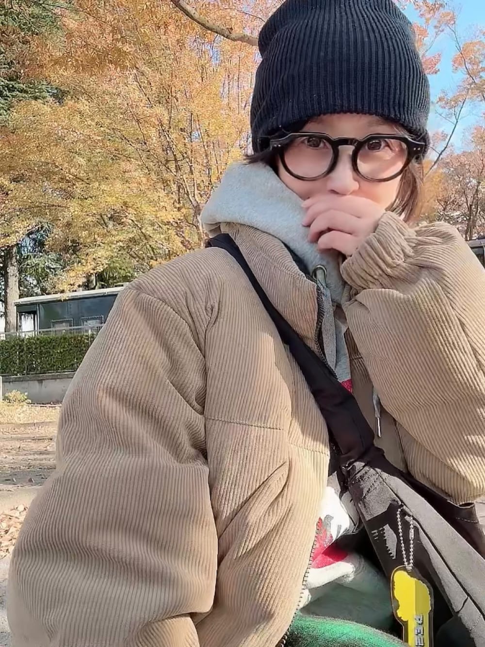 ベージュ系のダウンジャケット/コート、ブラック系のショルダーバッグ、グレー系のパーカーを着用したレディースの秋コーディネートの2枚目の写真