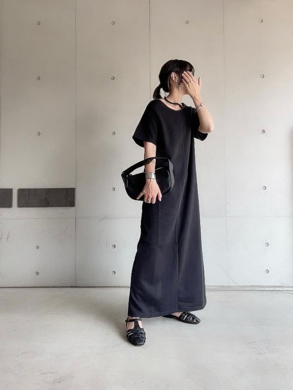 ブラック系のワンピース、ブラック系のハンドバッグ、ブラック系のサンダルを着用したレディースの夏コーディネートの2枚目の写真
