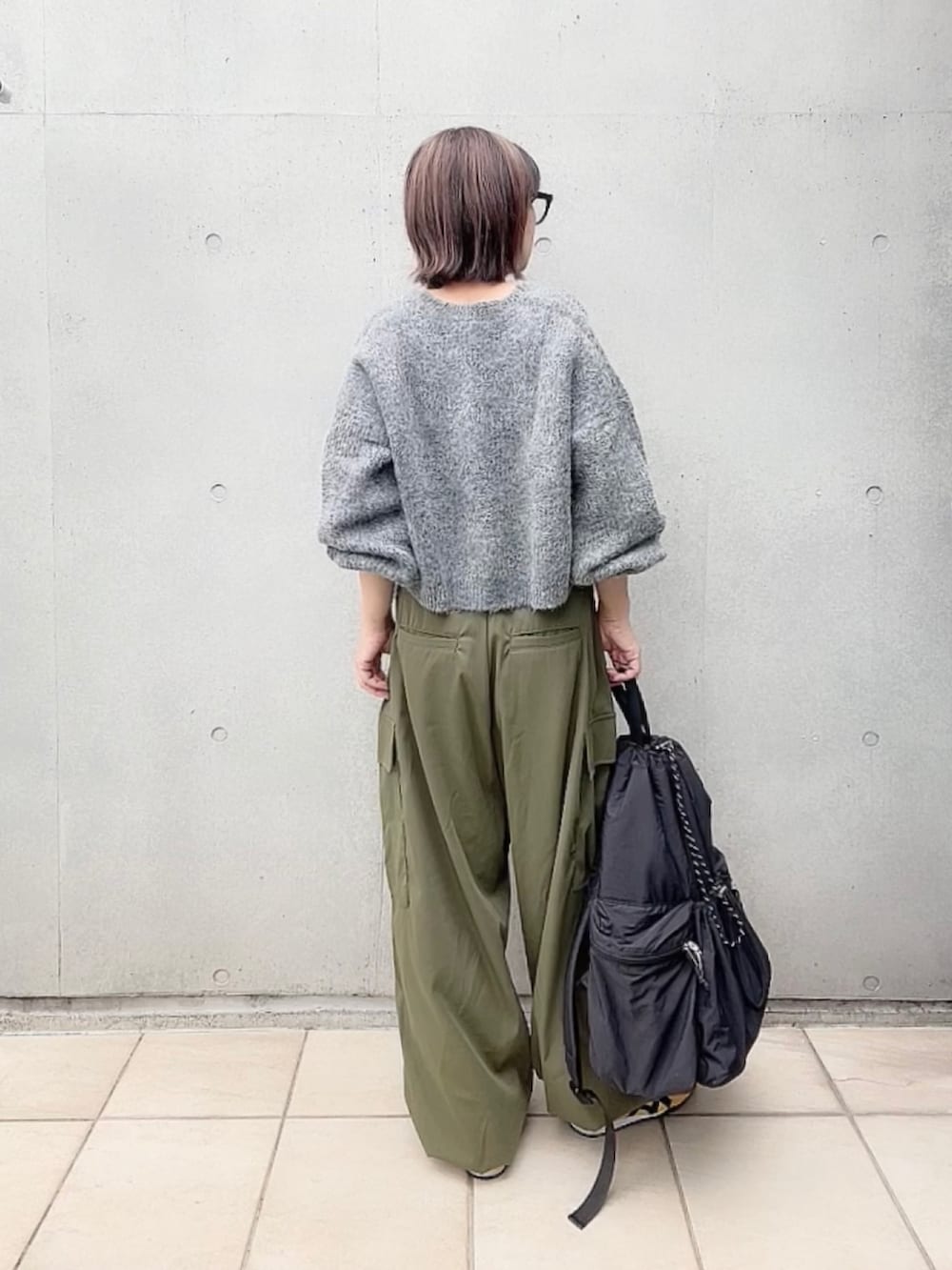グレー系のカーディガン/ボレロ、ホワイト系のキャミソール、グリーン系のカーゴパンツを着用したレディースの秋コーディネートの3枚目の写真
