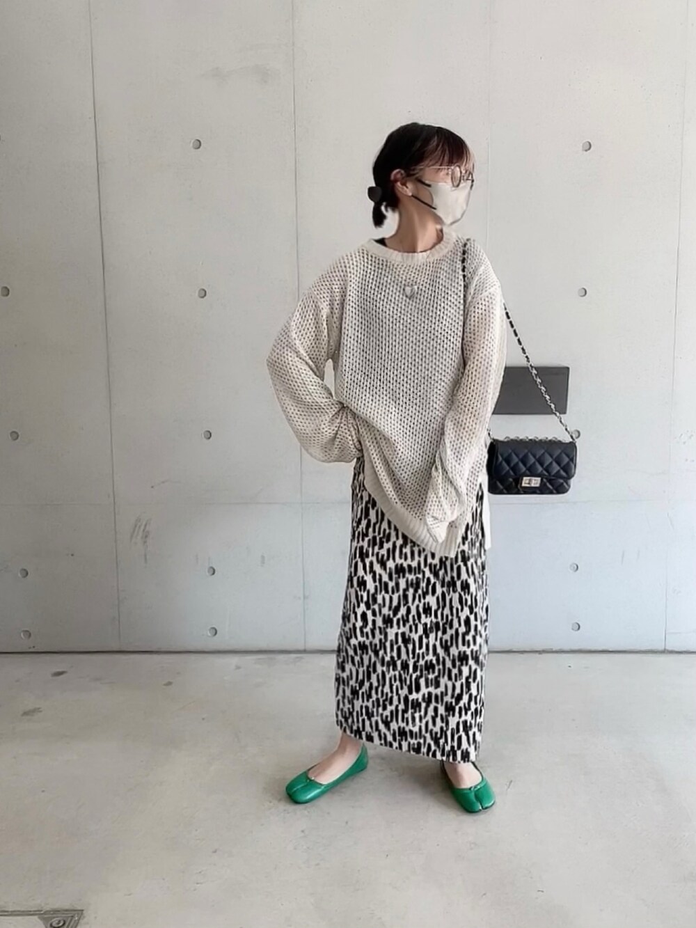 ホワイト系のニット/セーター、ホワイト系のスカート、ブラック系のショルダーバッグを着用したレディースの春コーディネートの2枚目の写真