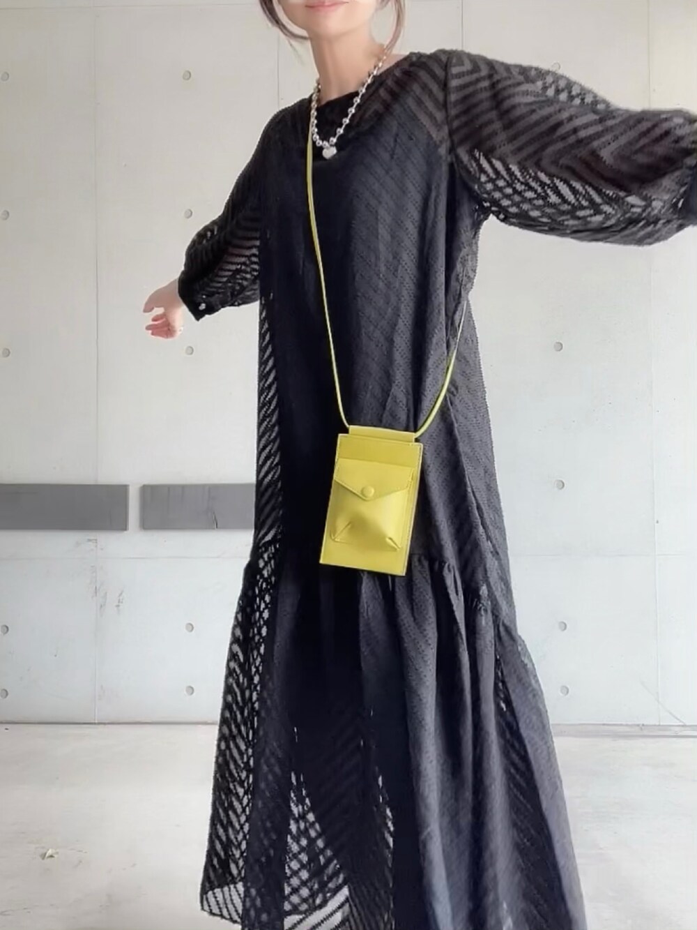 ブラック系のワンピース、グリーン系のショルダーバッグ、ホワイト系のパンプスを着用したレディースの夏コーディネートの5枚目の写真