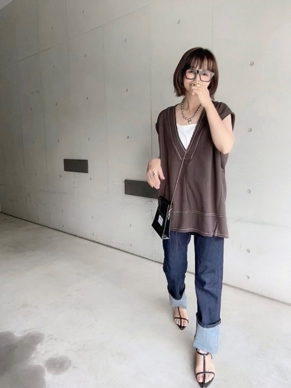 ブラウン系のベスト、ブルー系のデニムパンツ、ブラック系のサンダルを着用したレディースの夏コーディネートの4枚目の写真