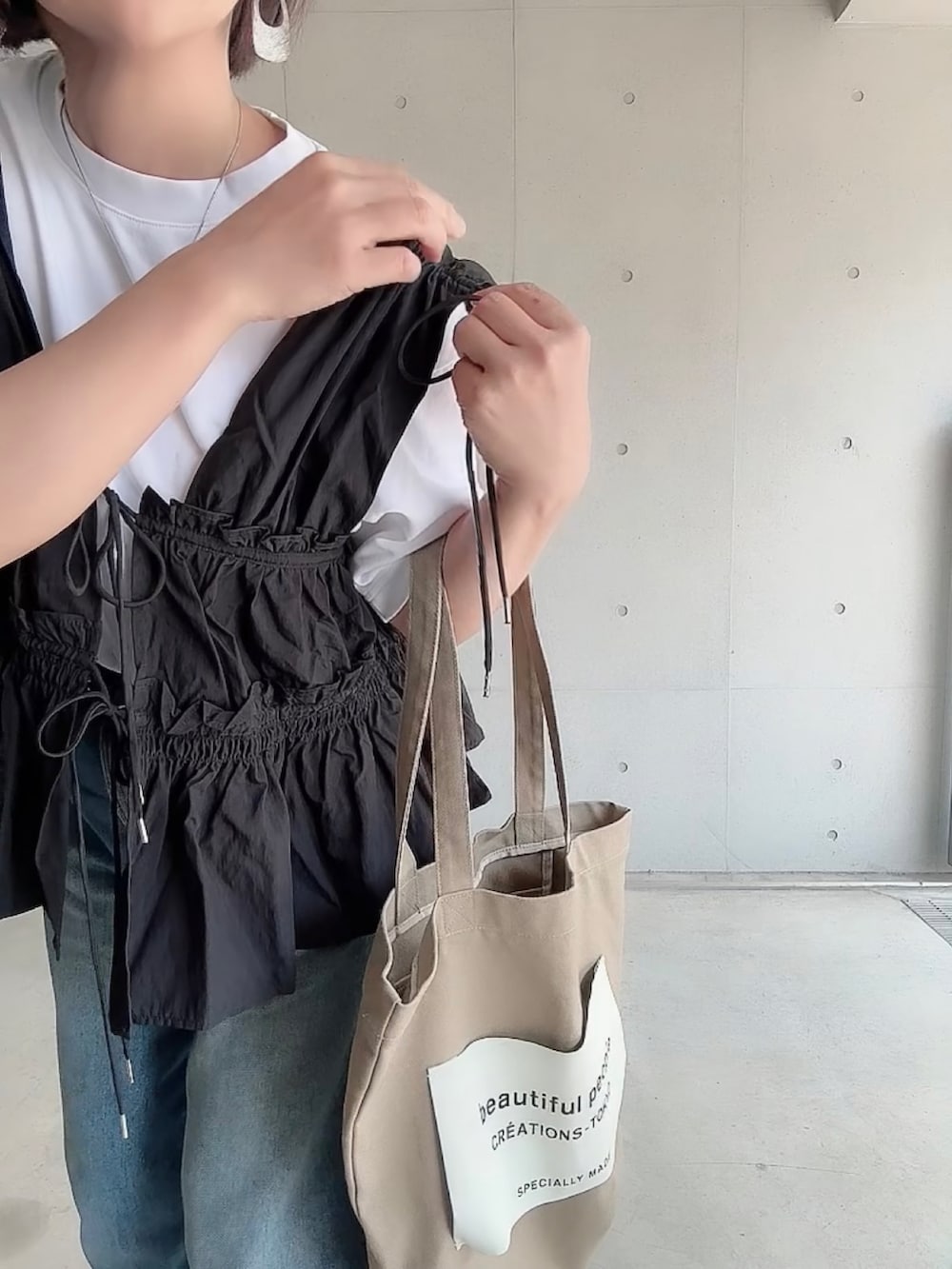 ブラック系のシャツ/ブラウス、ブルー系のデニムパンツ、ブラック系のパンプスを着用したレディースの夏コーディネートの4枚目の写真