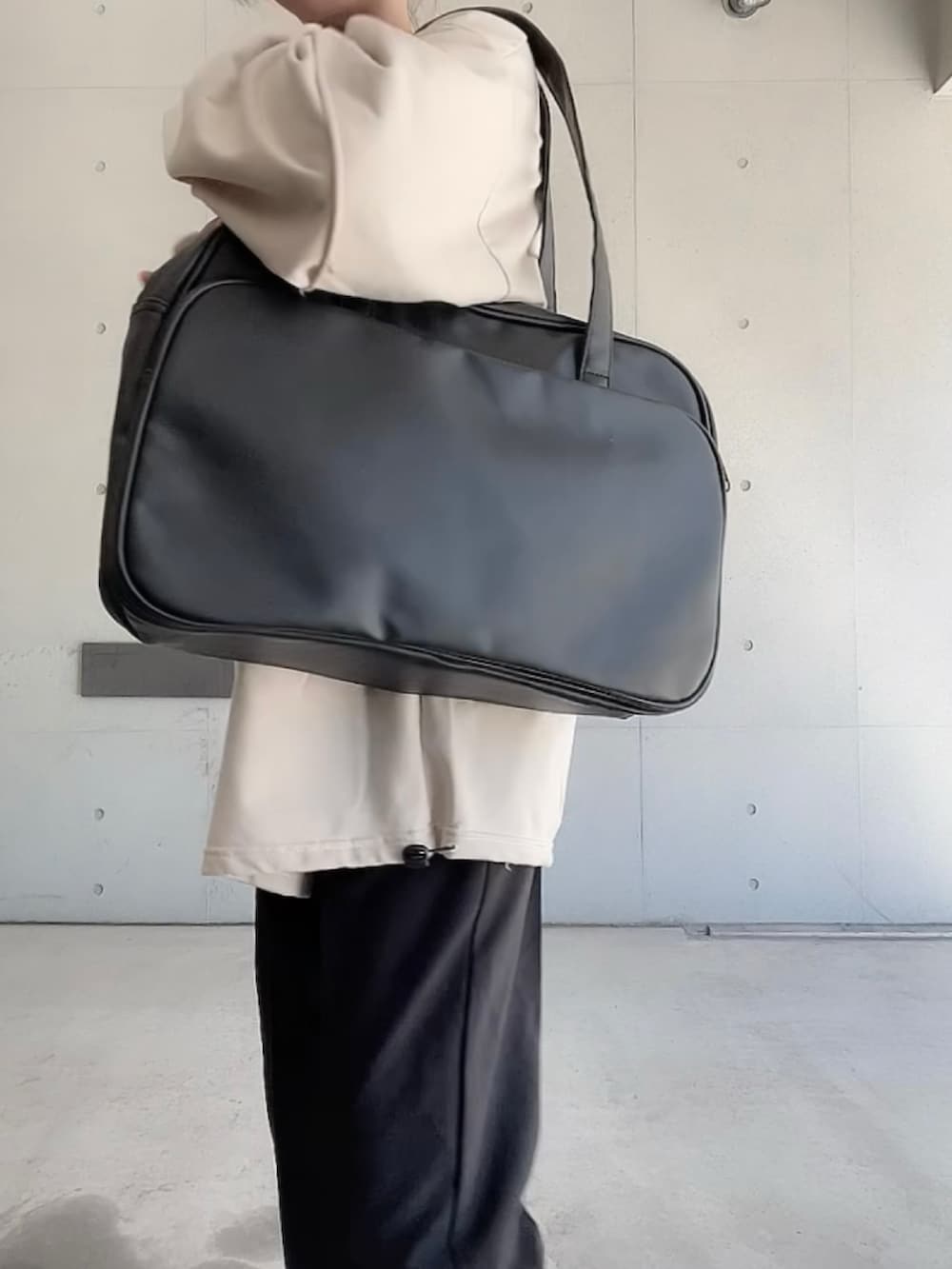 ブラック系のその他パンツ、ブラック系のボストンバッグ、ベージュ系のTシャツ/カットソーを着用したレディースの秋コーディネートの5枚目の写真