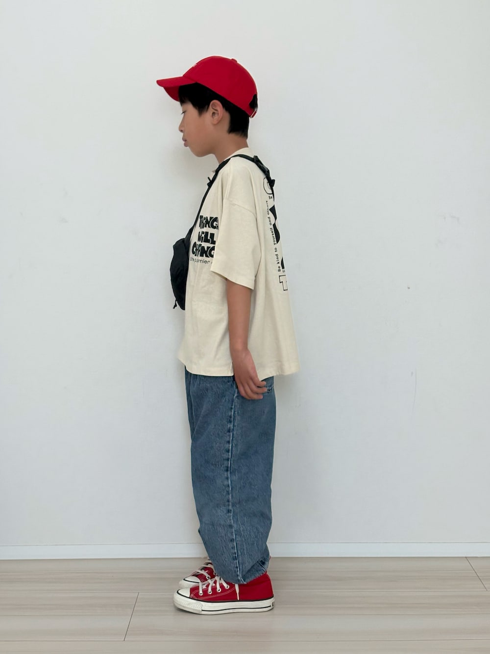 ホワイト系のTシャツ/カットソー、ブルー系のデニムパンツ、レッド系のスニーカーを着用したキッズの春コーディネートの3枚目の写真