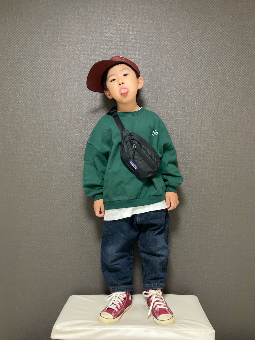 グリーン系のスウェット、ブルー系のデニムパンツ、レッド系のスニーカーを着用したキッズの秋コーディネートの2枚目の写真