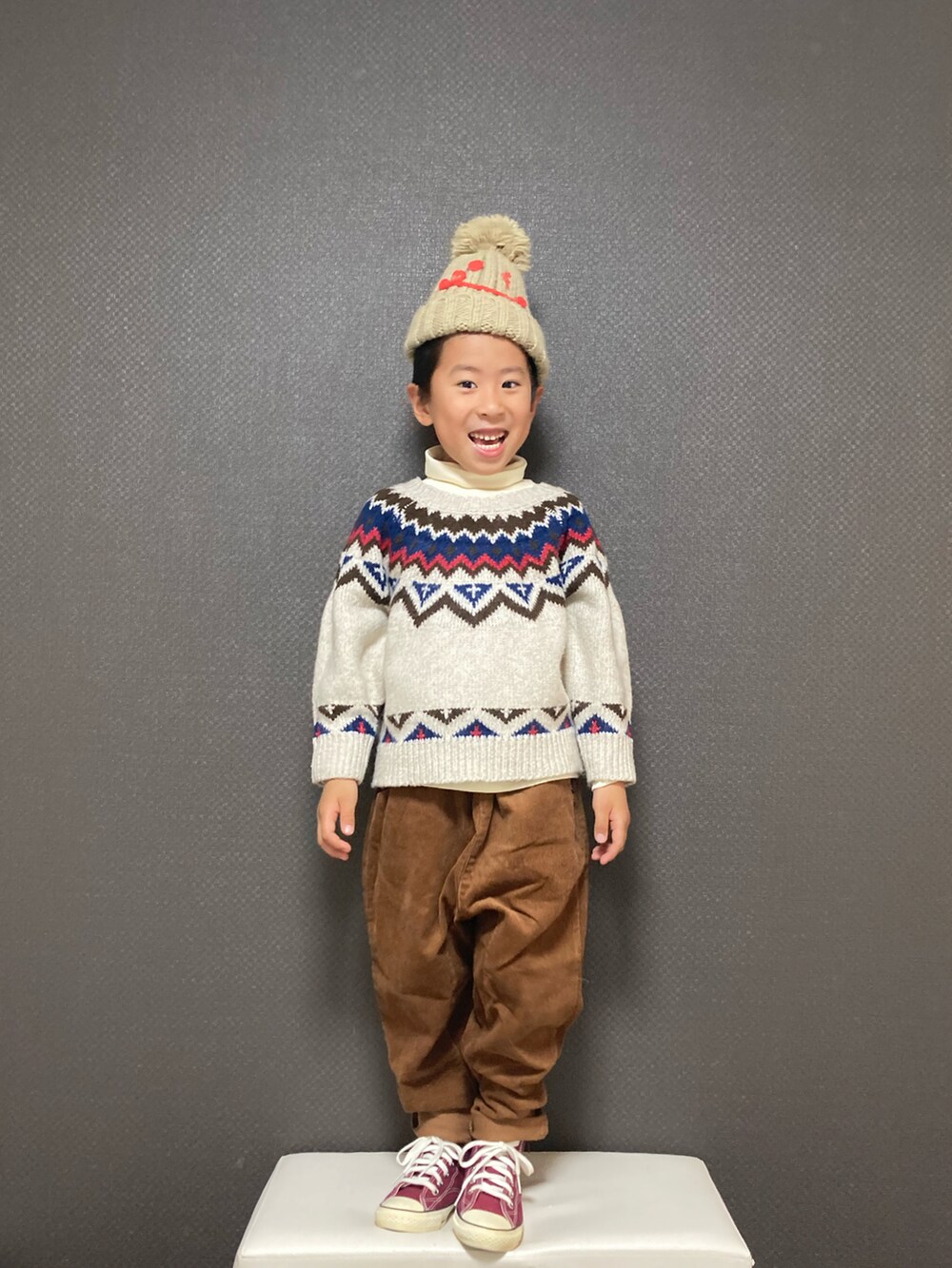 ホワイト系のカーディガン/ボレロ、ホワイト系のTシャツ/カットソー、ブラウン系のパンツを着用したキッズの冬コーディネートの2枚目の写真
