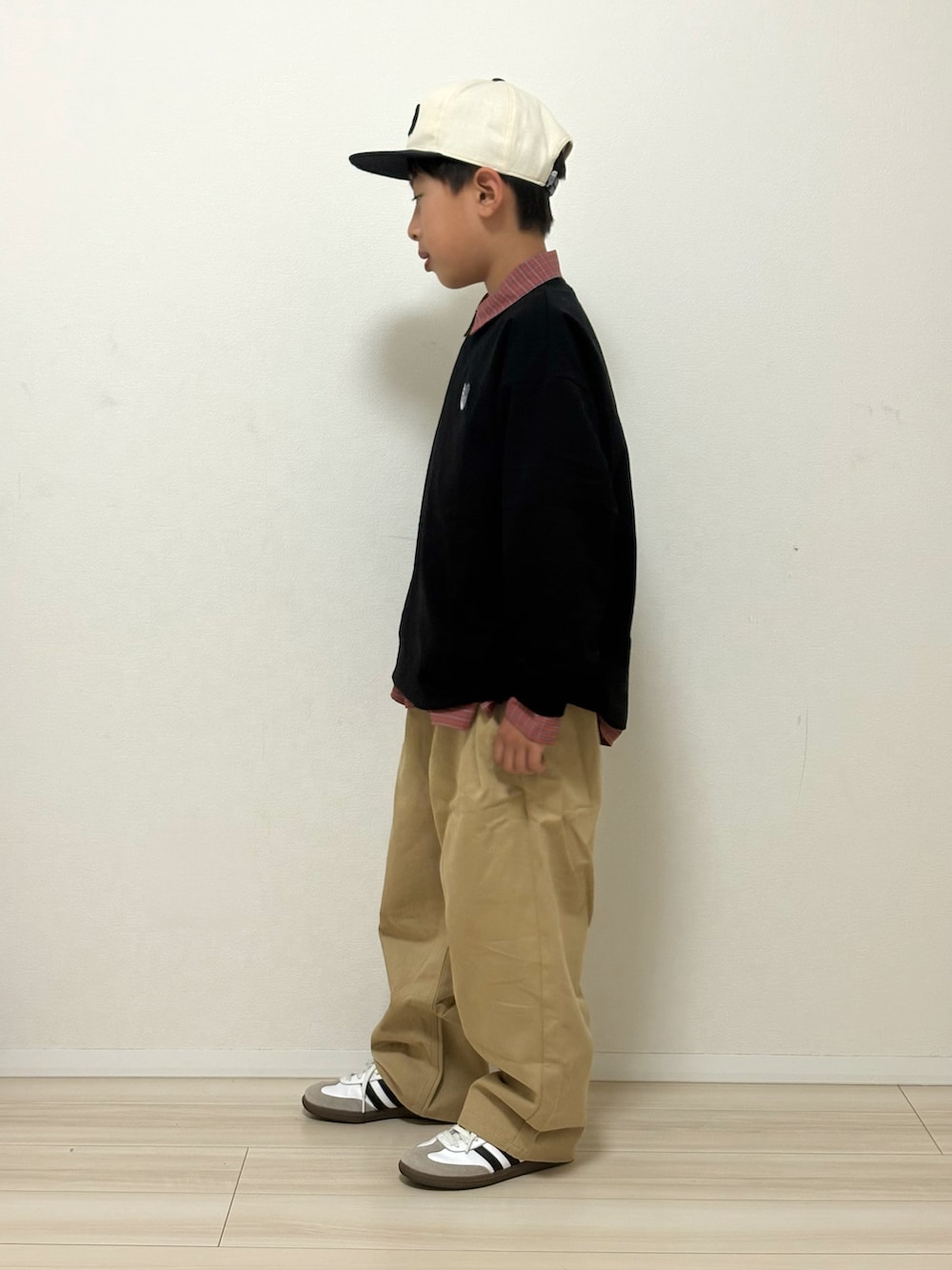 ブラック系のTシャツ/カットソー、ベージュ系のその他パンツ、ホワイト系のスニーカーを着用したキッズの冬コーディネートの3枚目の写真