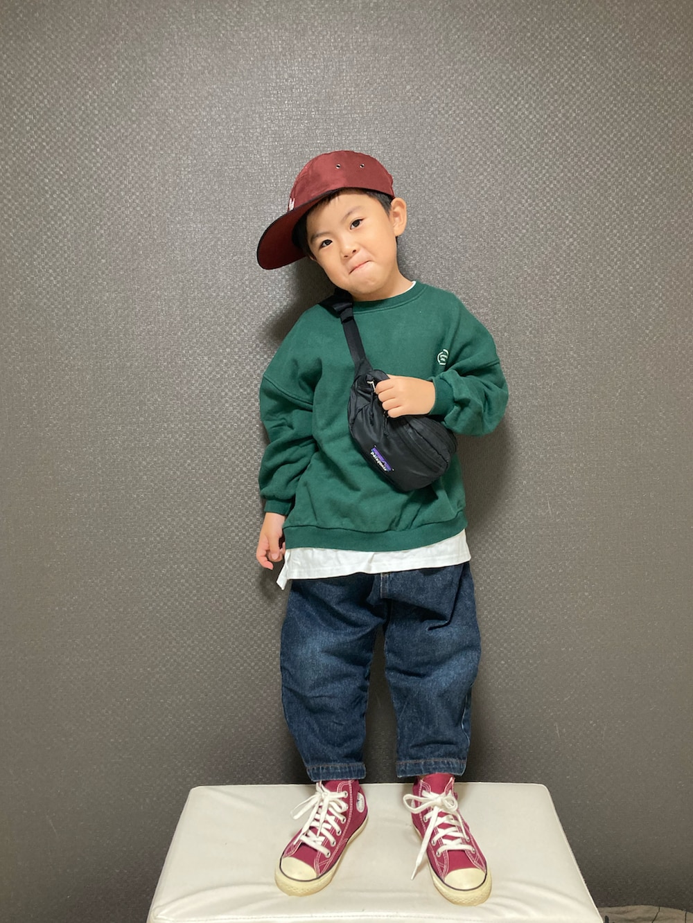 グリーン系のスウェット、ブルー系のデニムパンツ、レッド系のスニーカーを着用したキッズの秋コーディネートの3枚目の写真