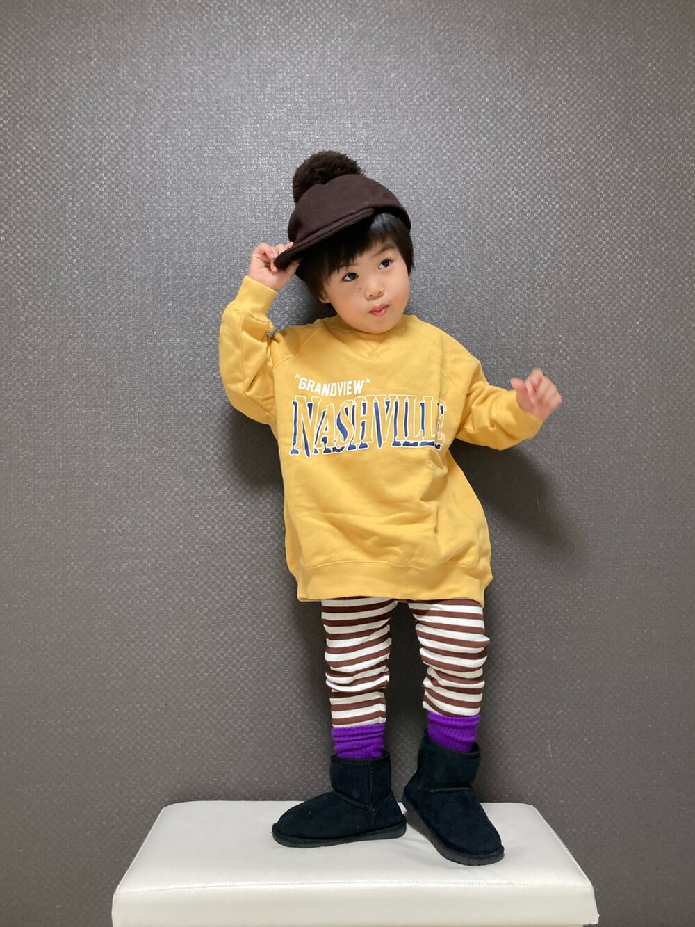 イエロー系のスウェット、ブラック系のブーツ、ブラウン系のキャップを着用したキッズの冬コーディネートの2枚目の写真