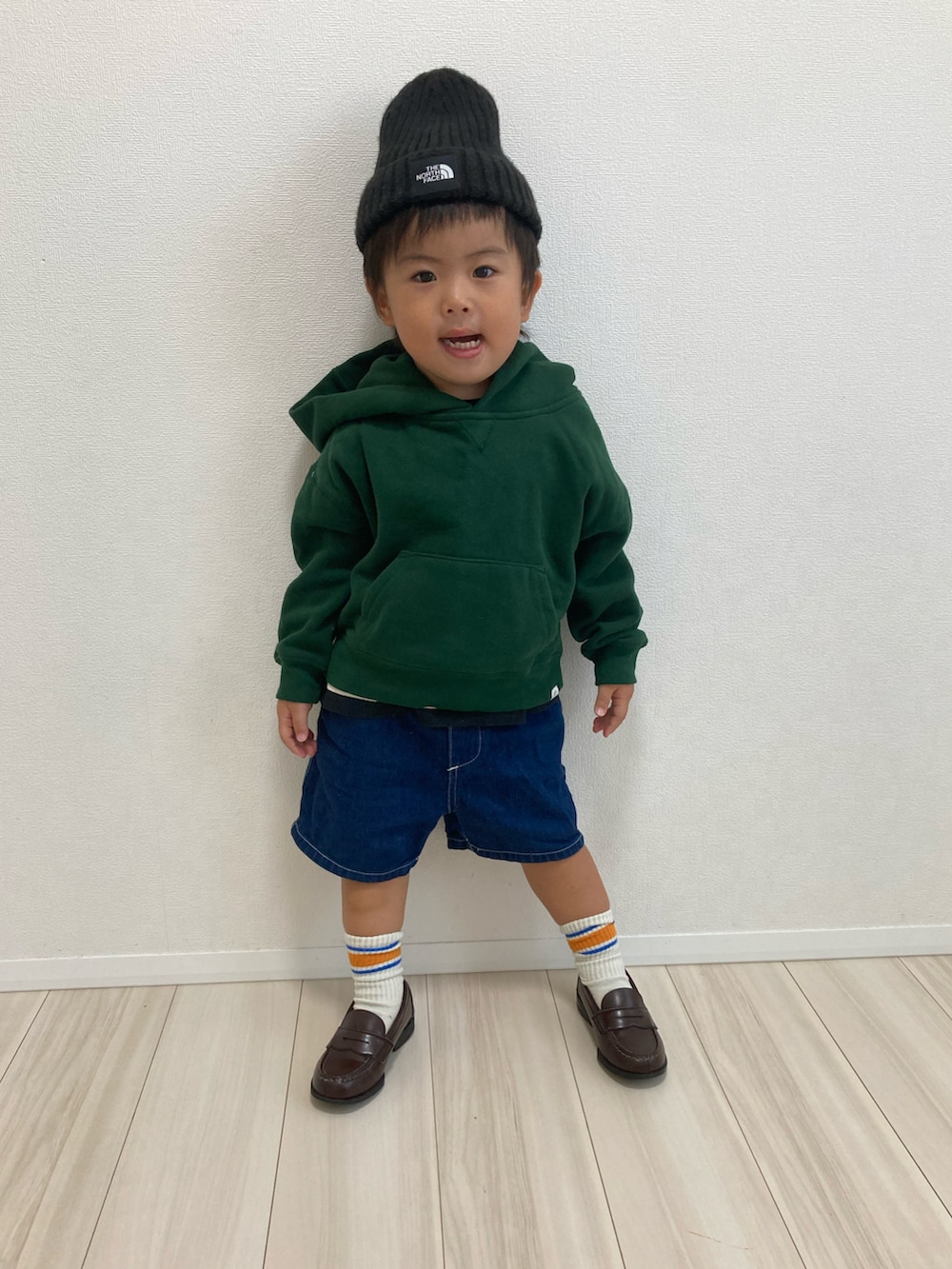 グリーン系のパーカー、ブルー系のデニムパンツ、ブラウン系のローファーを着用したキッズの秋コーディネートの2枚目の写真