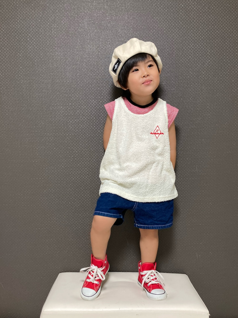 ホワイト系のタンクトップ、ブルー系のデニムパンツ、レッド系のスニーカーを着用したキッズの夏コーディネートの2枚目の写真