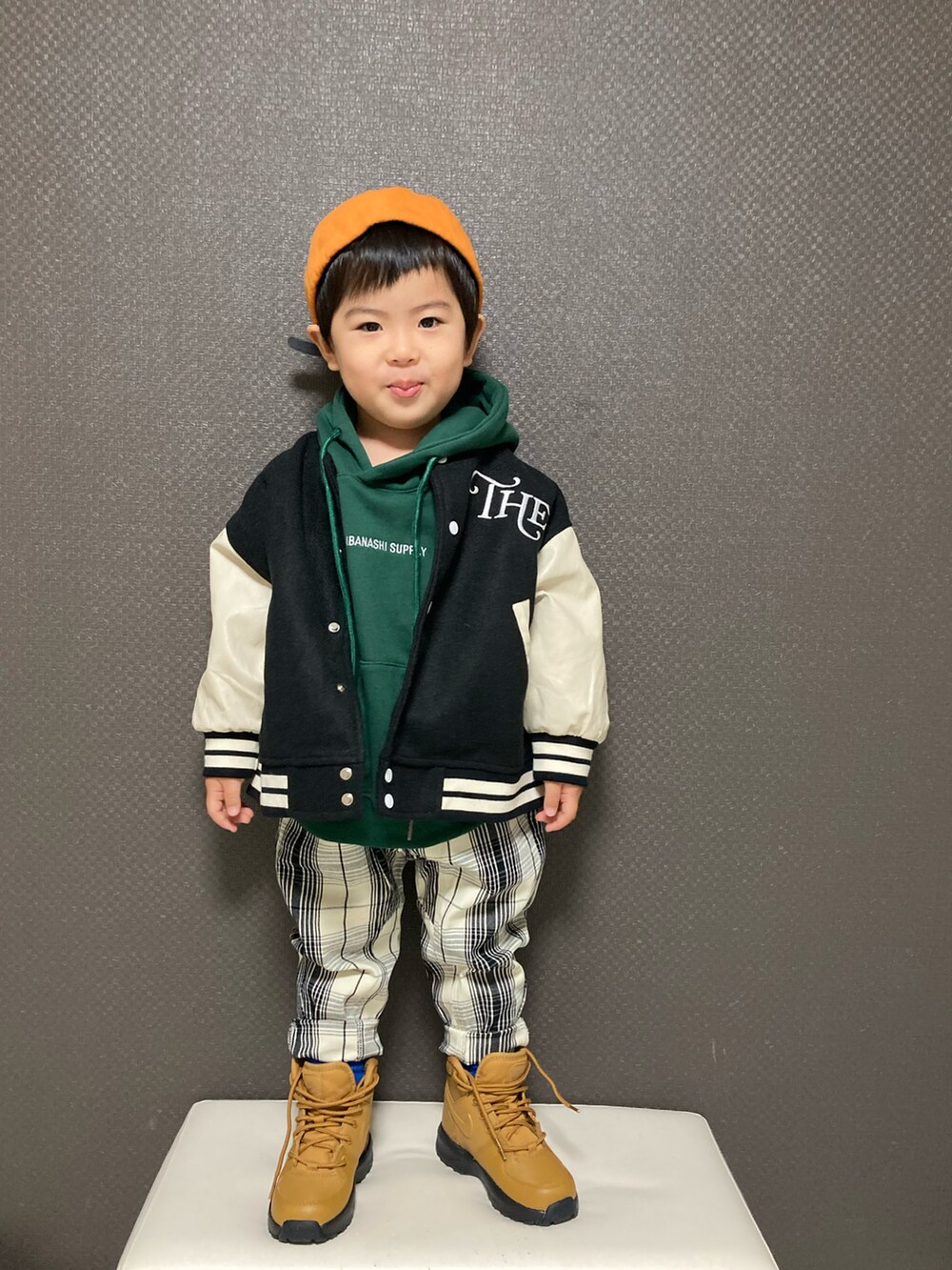 グリーン系のパーカー、ブラック系のスタジャン、ホワイト系のチノパンツを着用したキッズの冬コーディネートの2枚目の写真