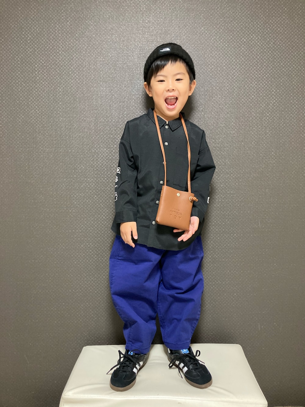 ブラック系のシャツ/ブラウス、ブラウン系のショルダーバッグ、ブルー系のチノパンツを着用したキッズの秋コーディネートの2枚目の写真