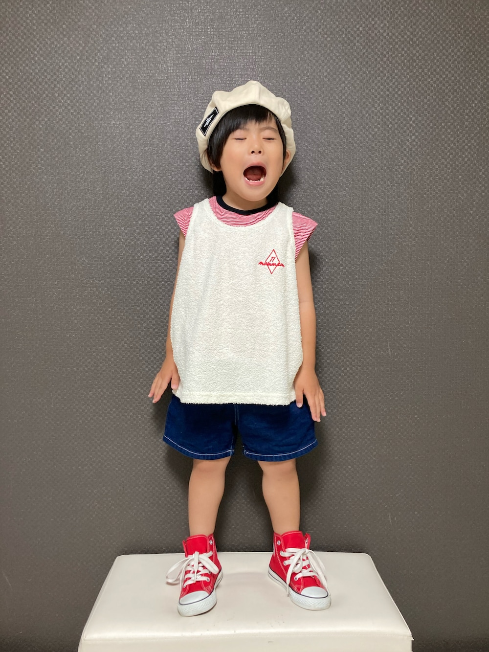 ホワイト系のタンクトップ、ブルー系のデニムパンツ、レッド系のスニーカーを着用したキッズの夏コーディネートの3枚目の写真
