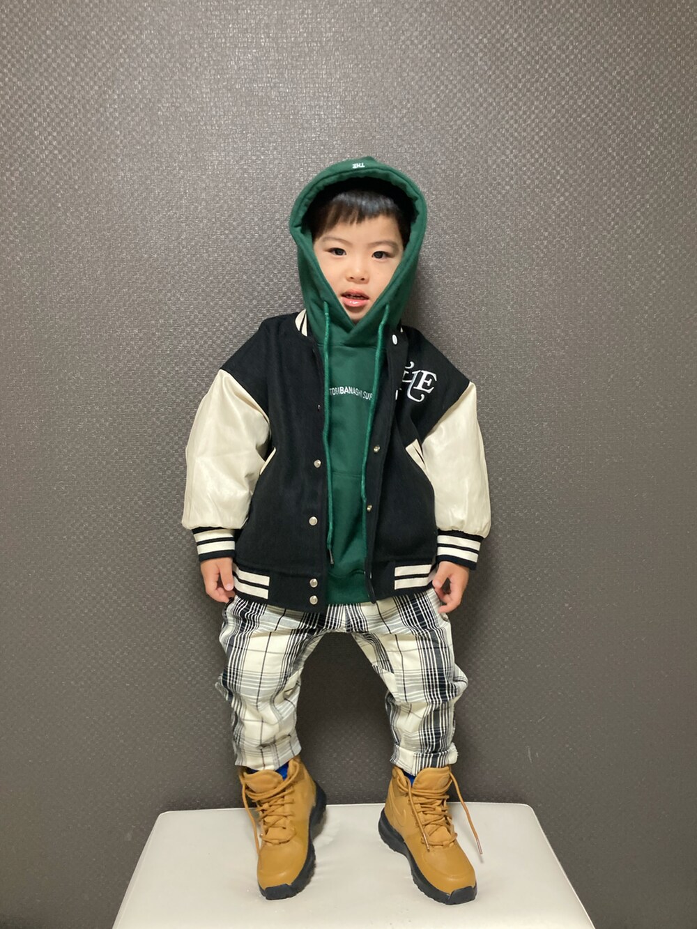 グリーン系のパーカー、ブラック系のスタジャン、ホワイト系のチノパンツを着用したキッズの冬コーディネートの3枚目の写真