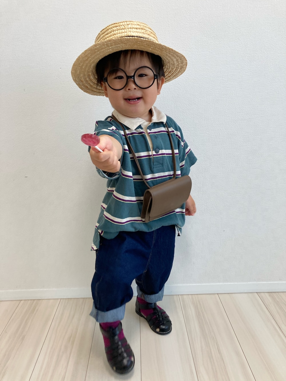 グリーン系のポロシャツ、ブラウン系のボディバッグ/ウエストポーチ、ブルー系のデニムパンツを着用したキッズの春コーディネートの3枚目の写真