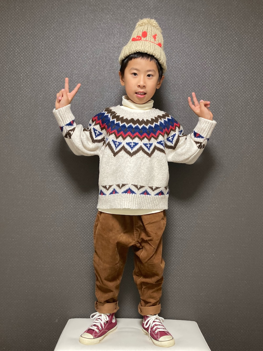 ホワイト系のカーディガン/ボレロ、ホワイト系のTシャツ/カットソー、ブラウン系のパンツを着用したキッズの冬コーディネートの4枚目の写真