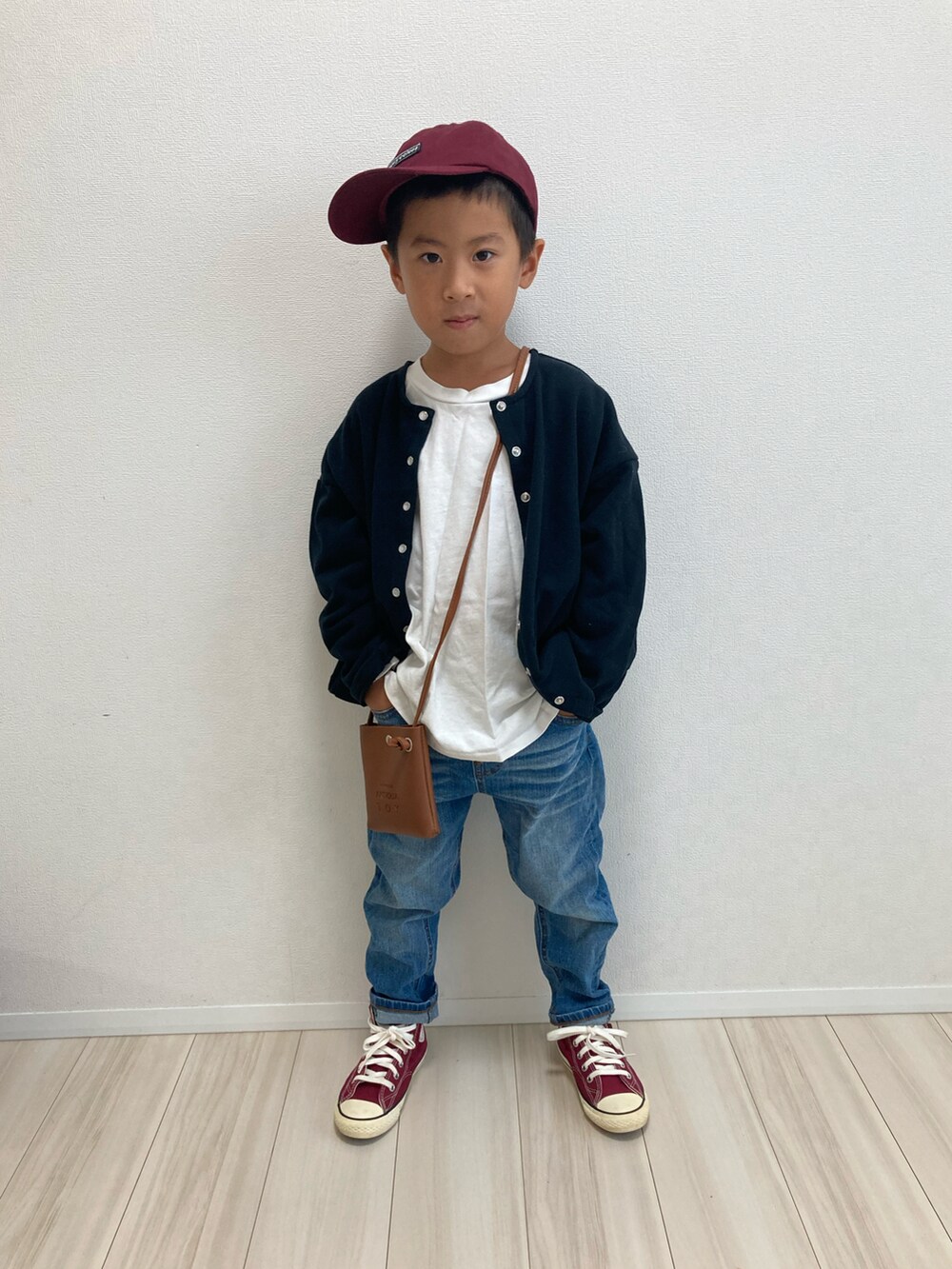 ホワイト系のTシャツ/カットソー、ブラウン系のショルダーバッグ、ブラック系のカーディガン/ボレロを着用したキッズの秋コーディネートの2枚目の写真