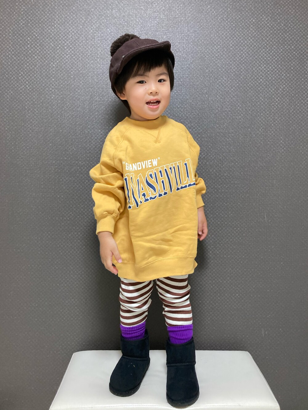 イエロー系のスウェット、ブラック系のブーツ、ブラウン系のキャップを着用したキッズの冬コーディネートの3枚目の写真