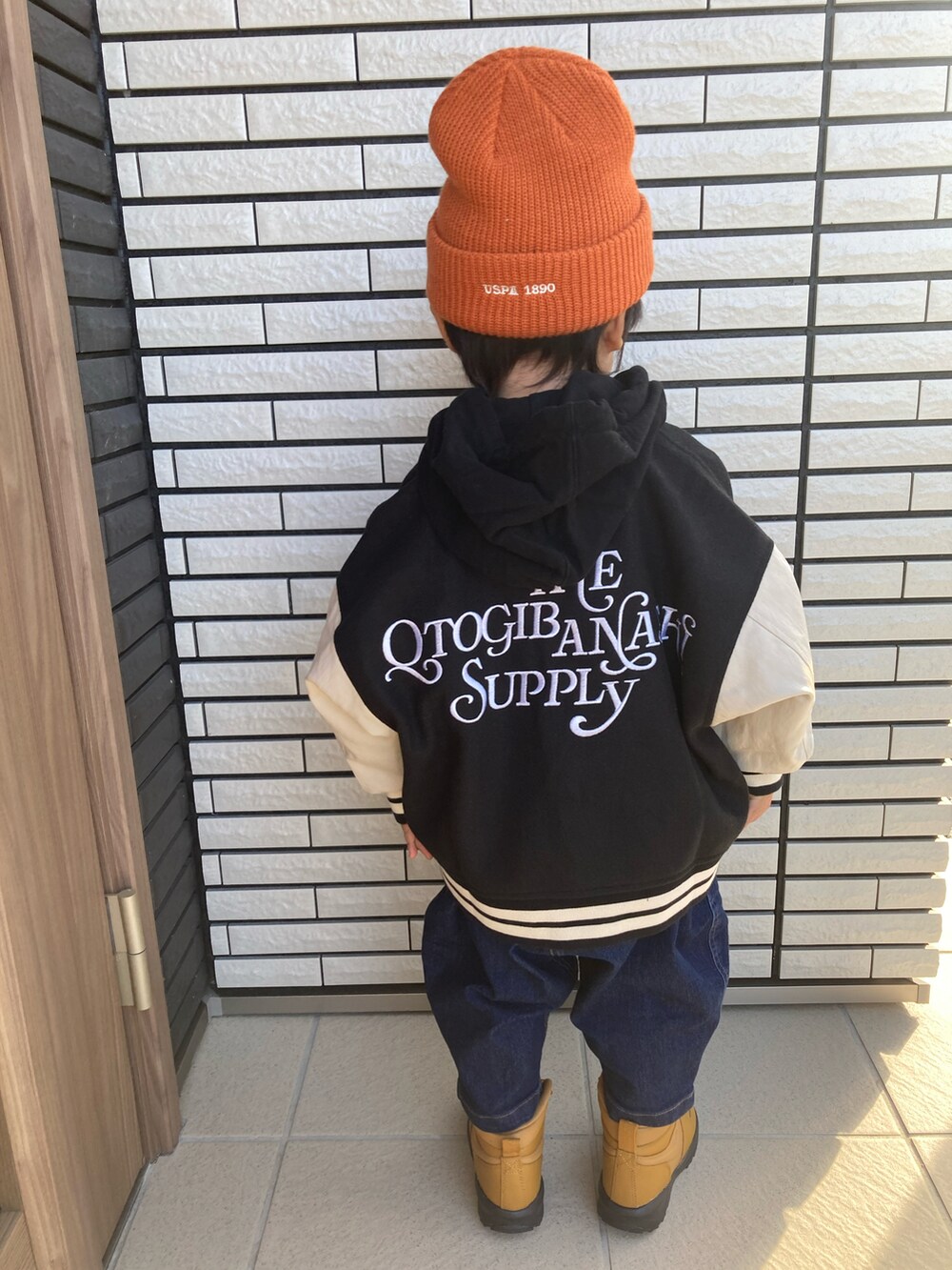 ブラック系のスタジャン、ブラック系のパーカー、ブルー系のデニムパンツを着用したキッズの冬コーディネートの2枚目の写真