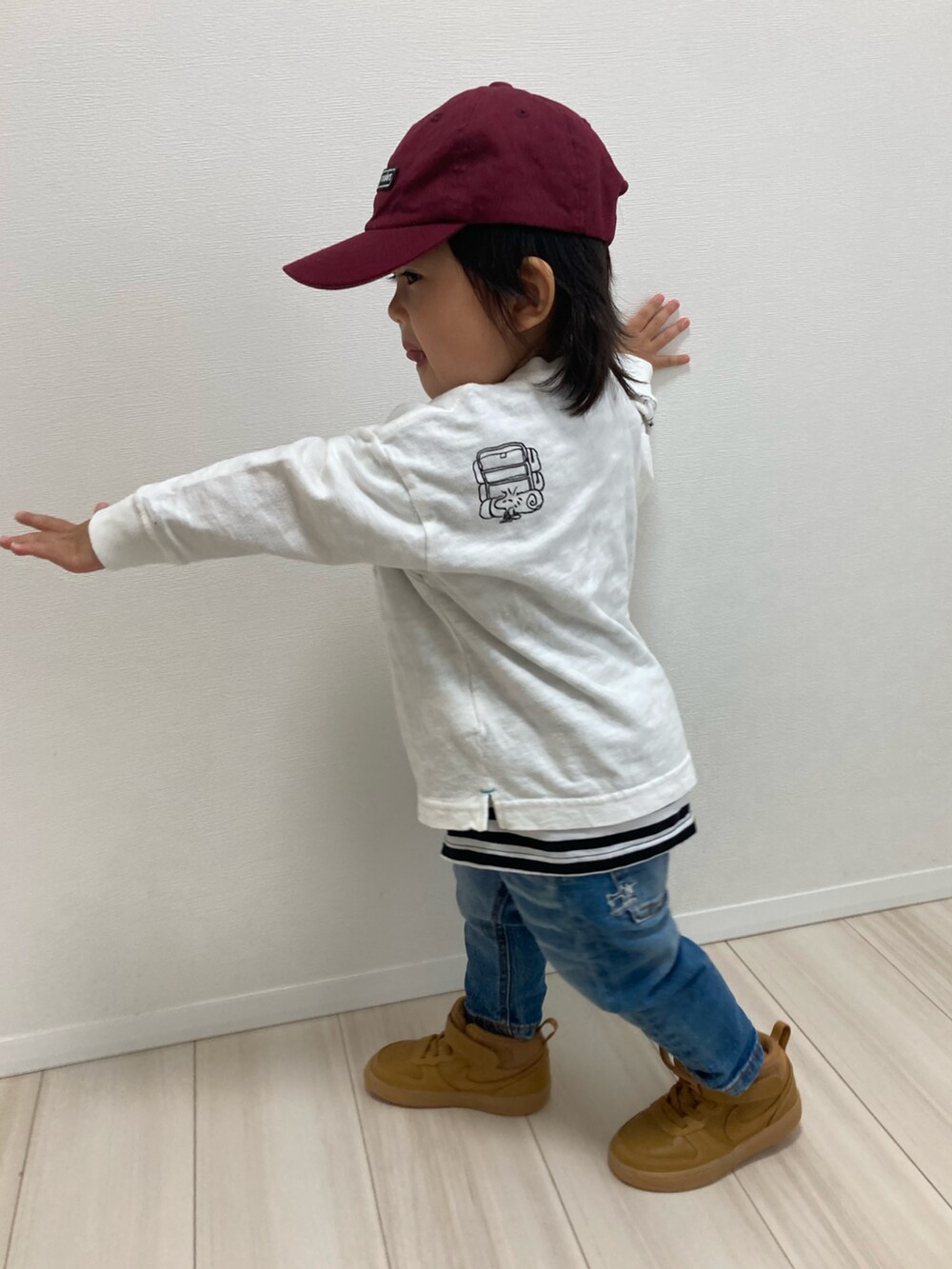 ホワイト系のTシャツ/カットソー、ブルー系のデニムパンツ、ブラウン系のスニーカーを着用したキッズの冬コーディネートの3枚目の写真