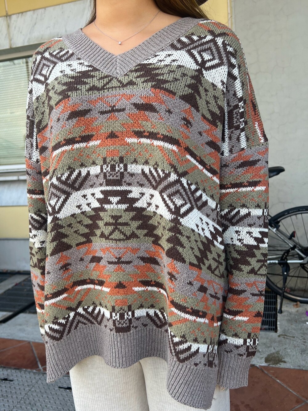 グリーン系のブルゾン、ベージュ系のニット/セーター、ホワイト系のその他パンツを着用したレディースの冬コーディネートの4枚目の写真