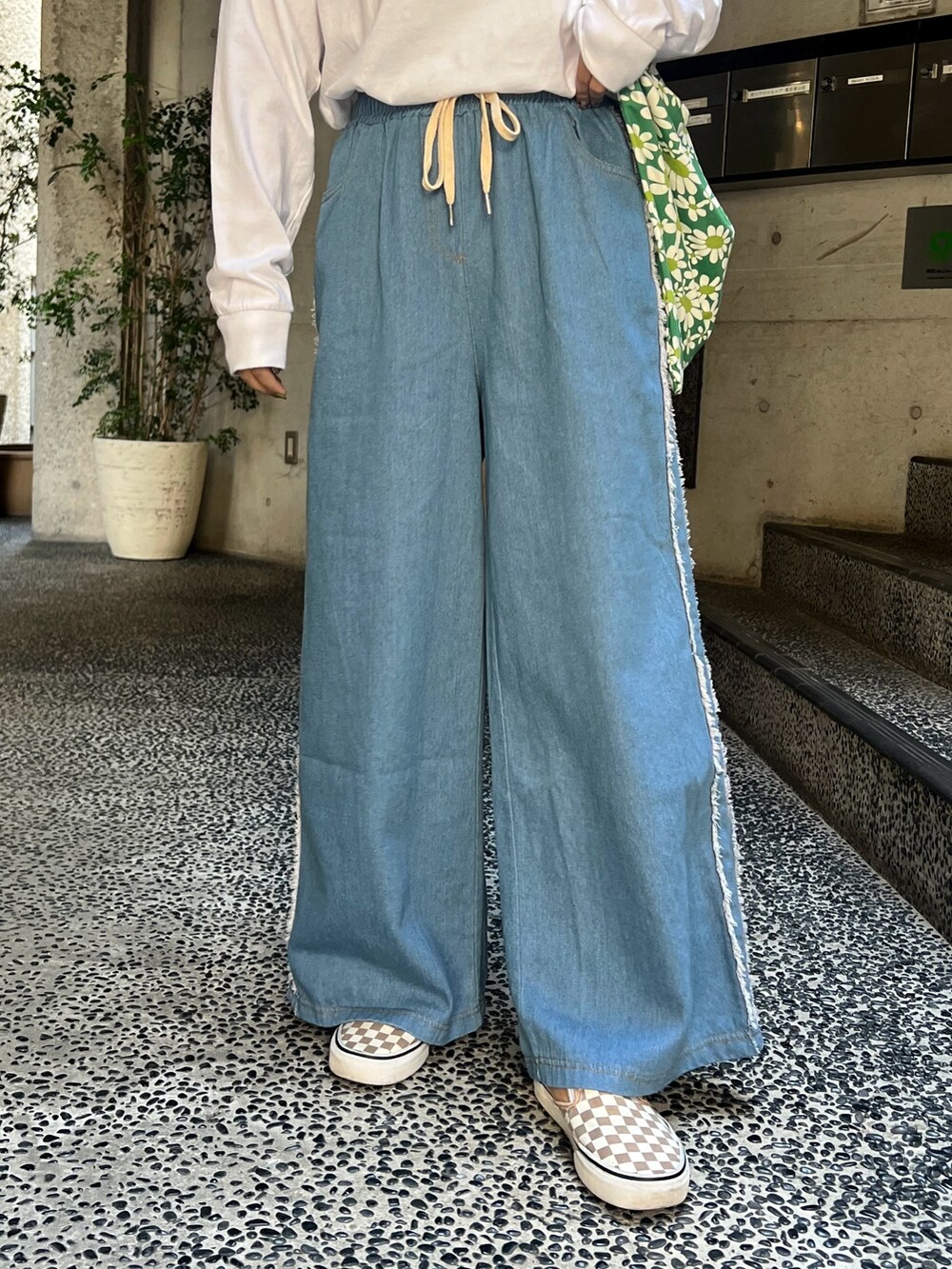 ブルー系のデニムパンツ、ベージュ系のスニーカーを着用したレディースの春コーディネートの3枚目の写真