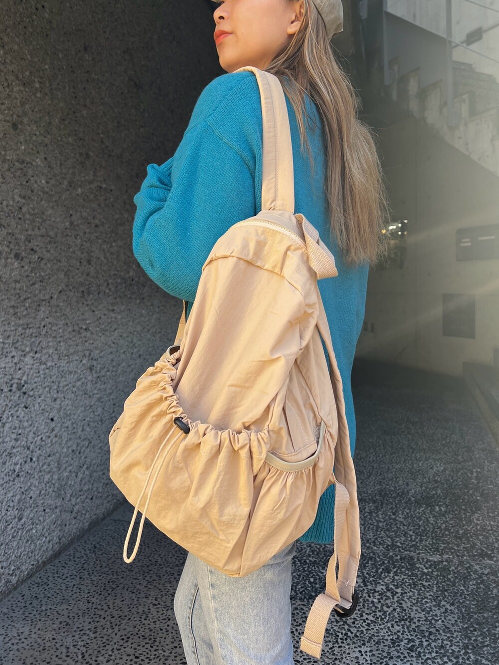 ブルー系のカーディガン/ボレロ、ベージュ系のバックパック/リュック、ベージュ系のスニーカーを着用したレディースの冬コーディネートの5枚目の写真