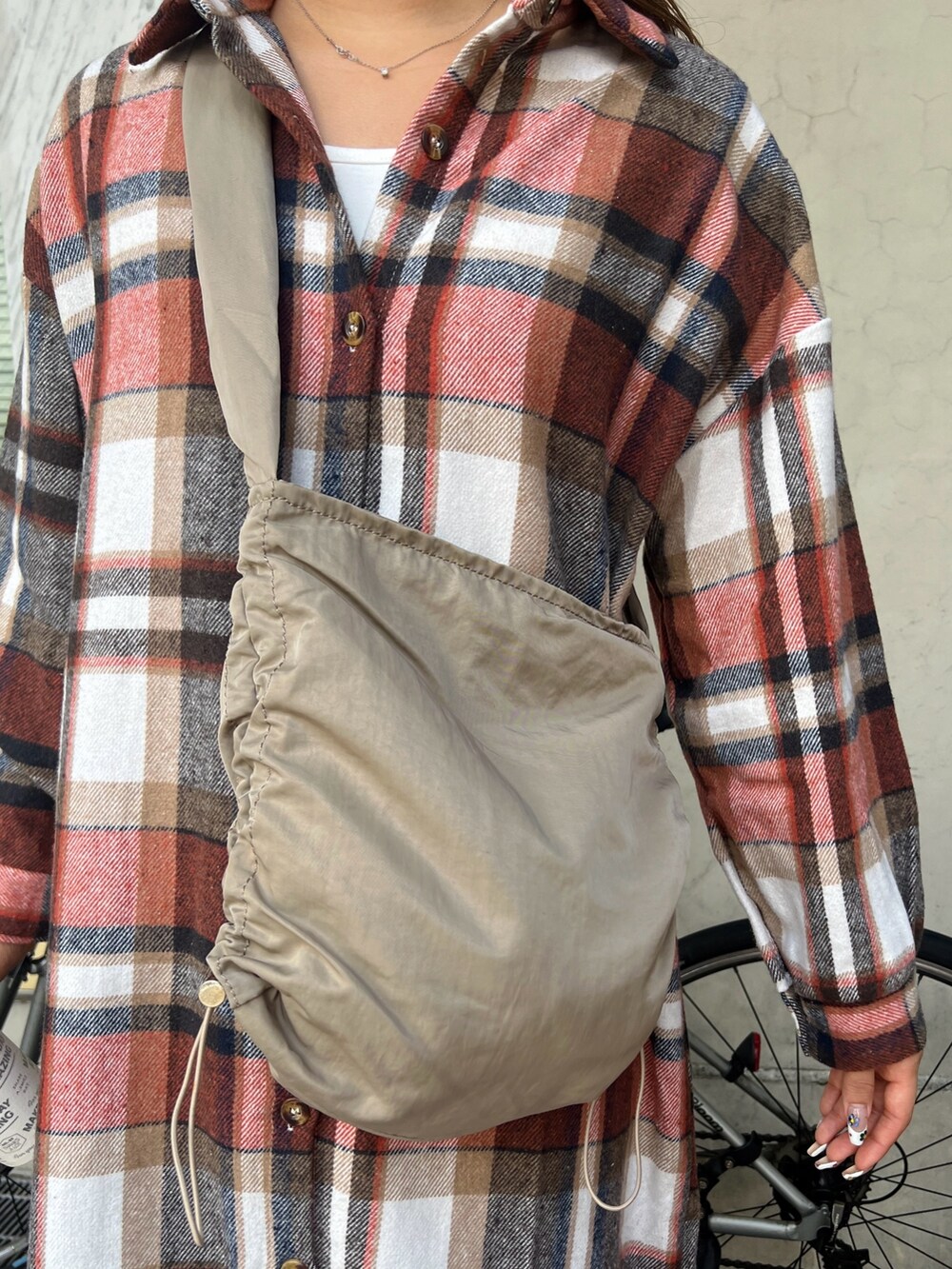 ベージュ系のショルダーバッグ、オレンジ系のワンピース、その他のスニーカーを着用したレディースの冬コーディネートの5枚目の写真