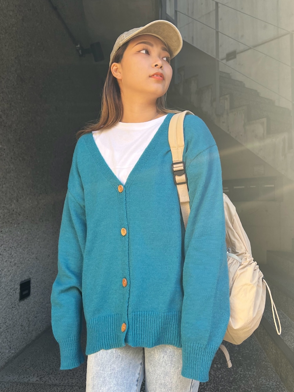 ブルー系のカーディガン/ボレロ、ベージュ系のバックパック/リュック、ベージュ系のスニーカーを着用したレディースの冬コーディネートの3枚目の写真