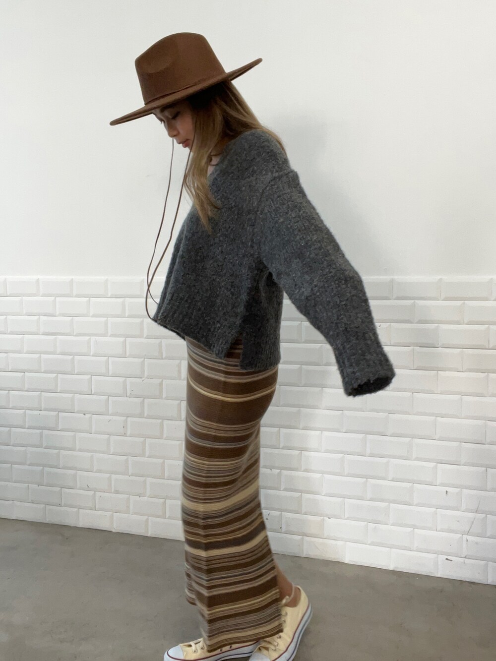 グレー系のニット/セーター、ブラウン系のスカート、その他のスニーカーを着用したレディースの秋コーディネートの2枚目の写真