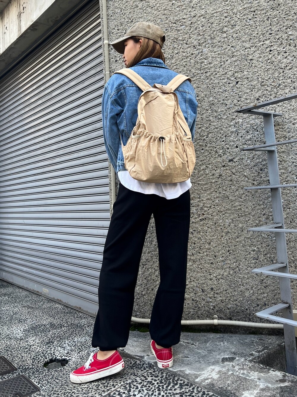 ベージュ系のバックパック/リュック、ブラック系のその他パンツ、レッド系のスニーカーを着用したレディースの冬コーディネートの3枚目の写真