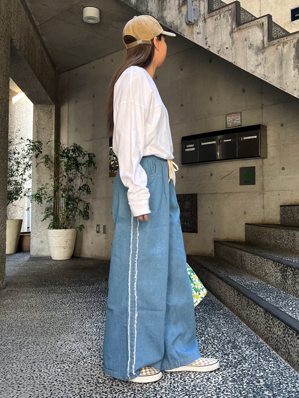 ブルー系のデニムパンツ、ベージュ系のスニーカーを着用したレディースの春コーディネートの2枚目の写真