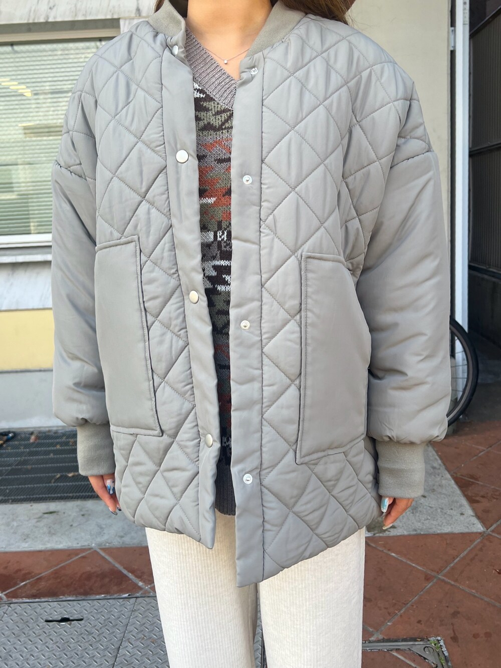 グリーン系のブルゾン、ベージュ系のニット/セーター、ホワイト系のその他パンツを着用したレディースの冬コーディネートの3枚目の写真