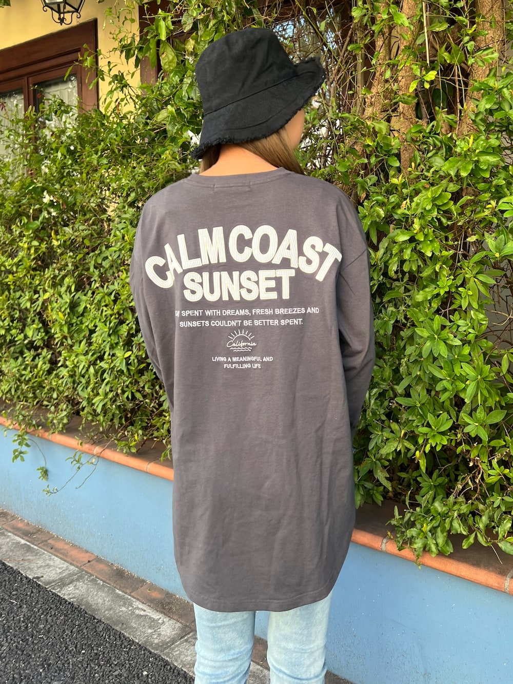グレー系のTシャツ/カットソー、ブルー系のデニムパンツ、ベージュ系のスニーカーを着用したレディースの春コーディネートの3枚目の写真