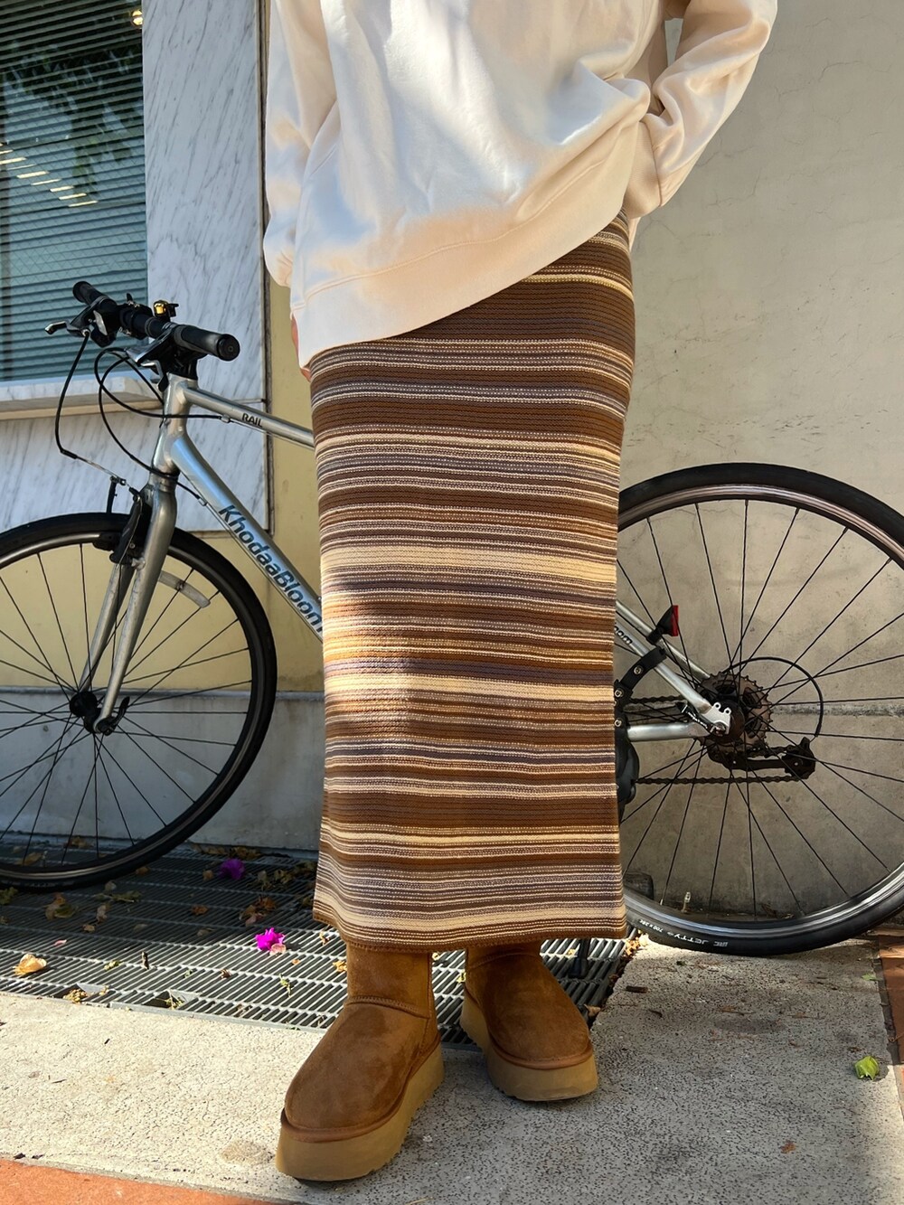 イエロー系のブーツ、ブラウン系のスカート、ベージュ系のスウェットを着用したレディースの冬コーディネートの6枚目の写真