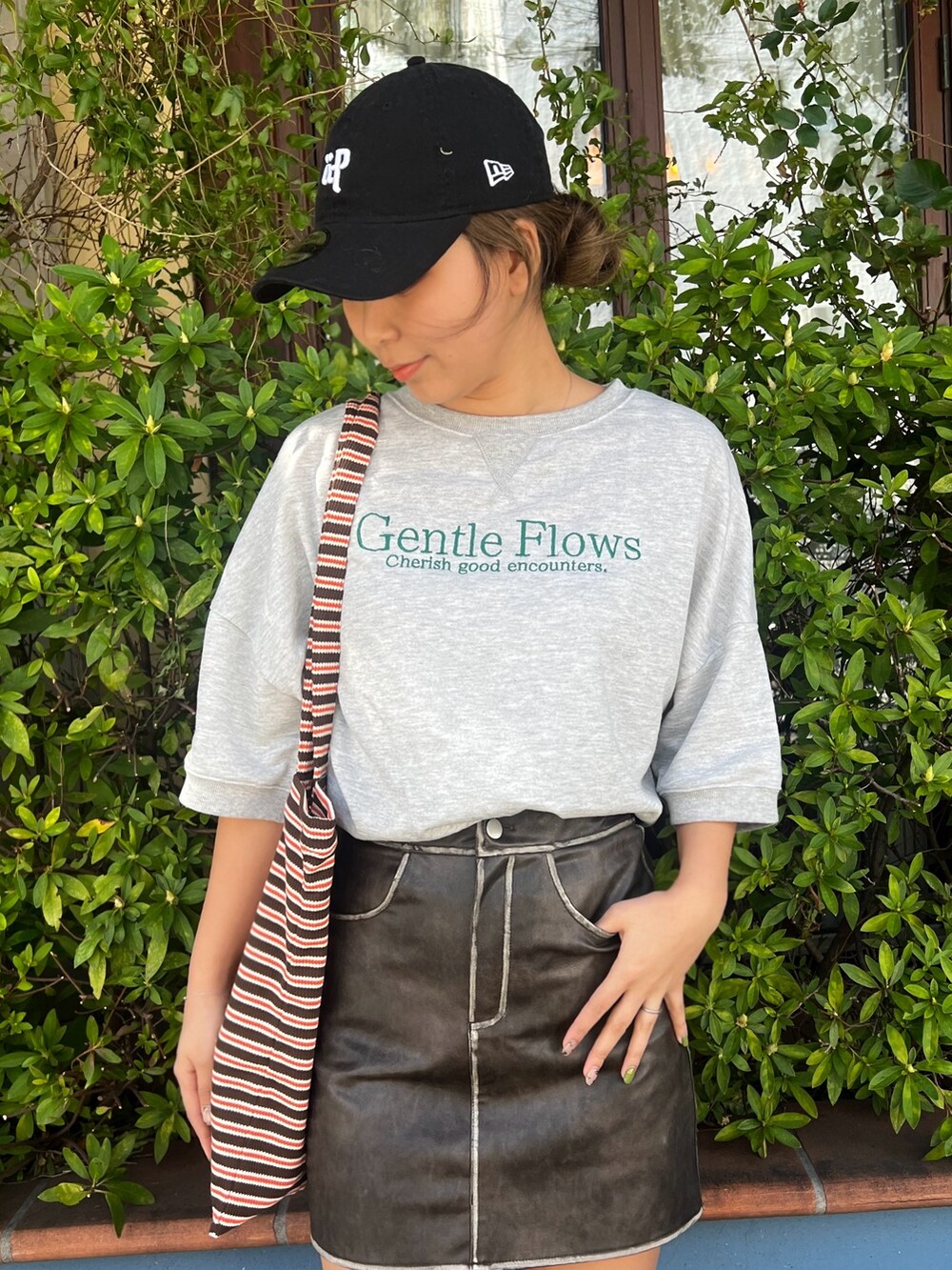 グレー系のTシャツ/カットソー、ブラウン系のスカート、グレー系のスニーカーを着用したレディースの春コーディネートの2枚目の写真