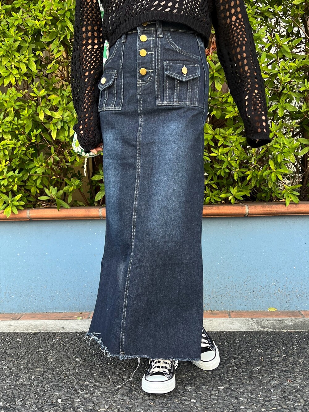 ブルー系のデニムスカート、ブラック系のTシャツ/カットソー、ブラック系のスニーカーを着用したレディースの春コーディネートの3枚目の写真