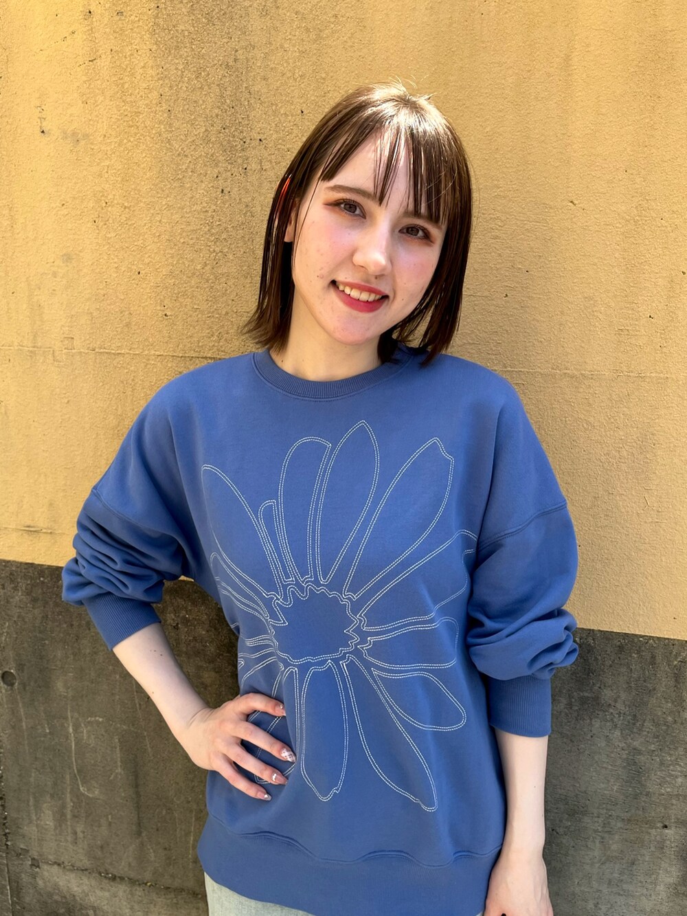 ブルー系のスウェット、オレンジ系のバレッタ/ヘアクリップを着用したレディースの春コーディネートの2枚目の写真