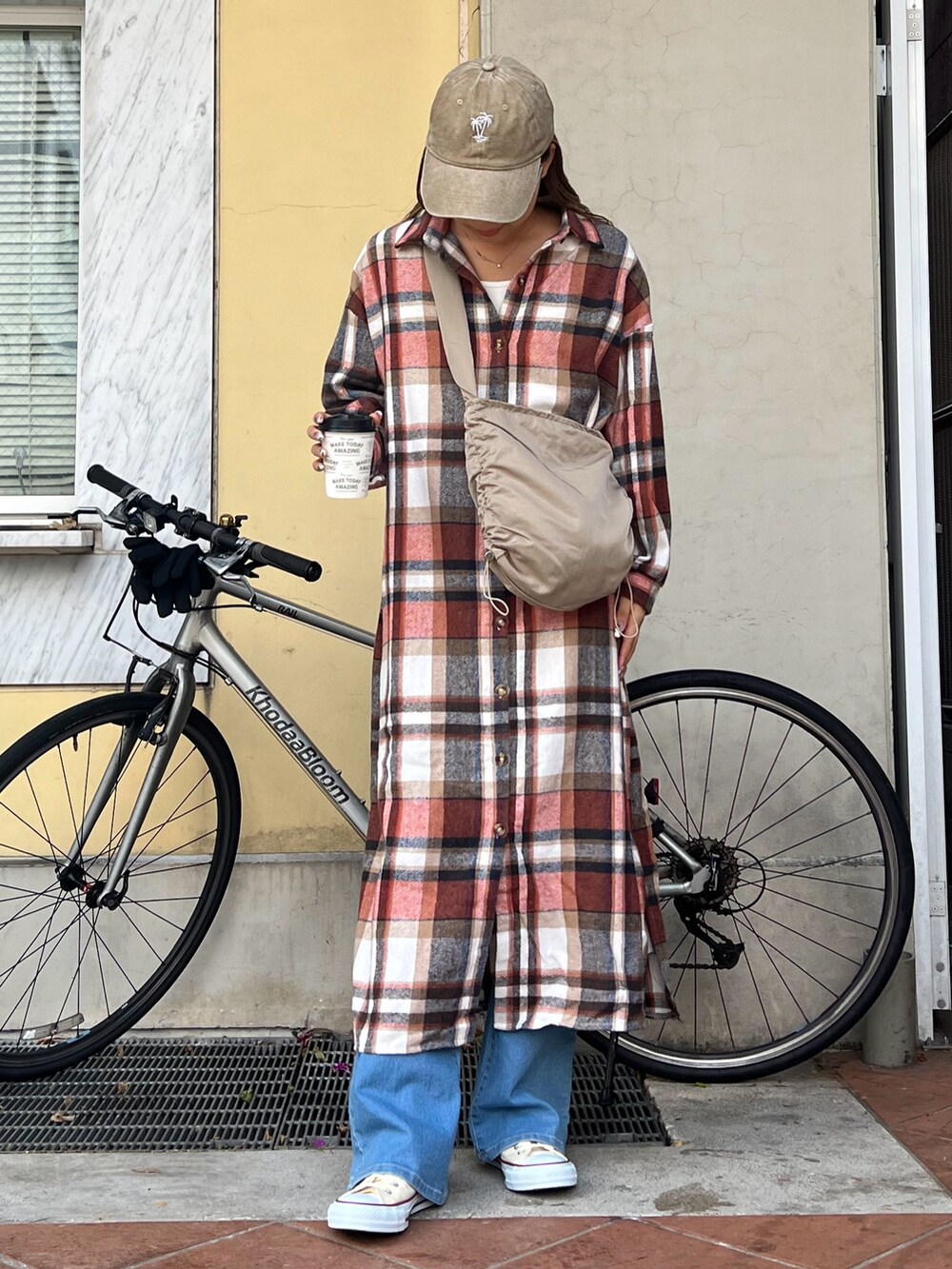 ベージュ系のショルダーバッグ、オレンジ系のワンピース、その他のスニーカーを着用したレディースの冬コーディネートの2枚目の写真