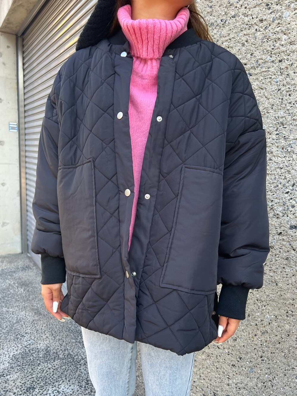 ブラック系のショルダーバッグ、ベージュ系のスニーカー、ブルー系のデニムパンツを着用したレディースの冬コーディネートの2枚目の写真