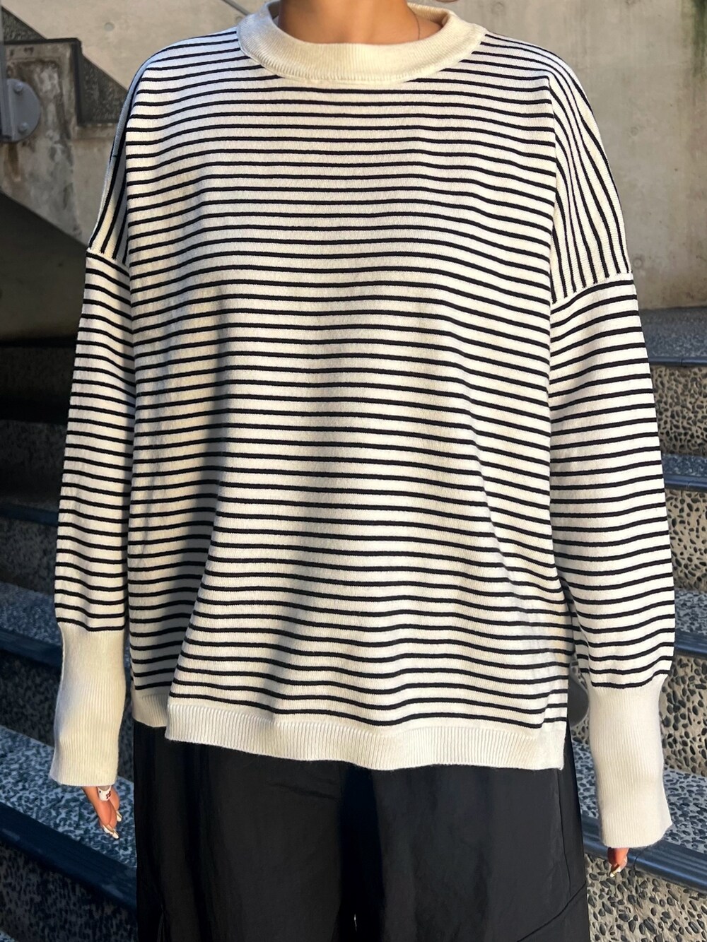 ブラック系のニット/セーター、ブラック系のショルダーバッグ、ブラック系のカーゴパンツを着用したレディースの春コーディネートの4枚目の写真