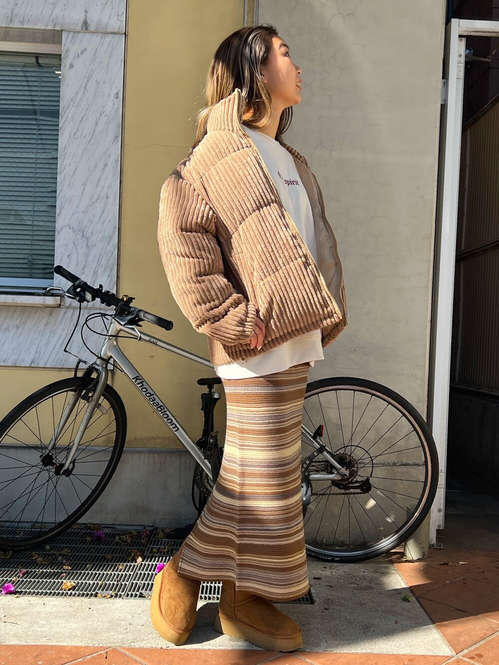 イエロー系のブーツ、ブラウン系のスカート、ベージュ系のスウェットを着用したレディースの冬コーディネートの2枚目の写真