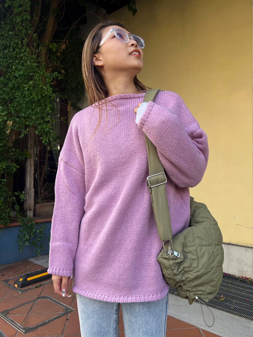 グリーン系のショルダーバッグ、パープル系のニット/セーター、ベージュ系のスニーカーを着用したレディースの冬コーディネートの2枚目の写真